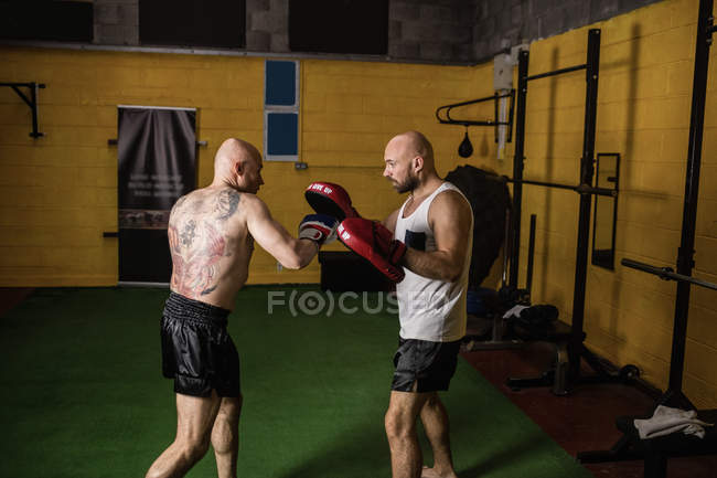 Vista lateral de dois boxers tailandeses musculares praticando no ginásio — Fotografia de Stock