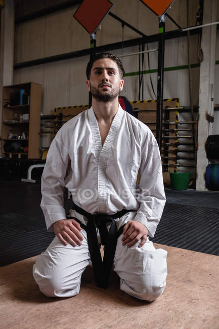 Mann im Karate-Kimono sitzt im Fitnessstudio auf dem Boden — Stockfoto