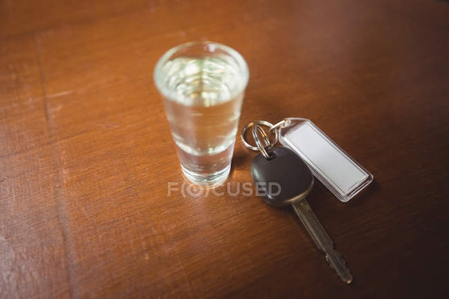 Стакан текилы с ключом от машины в барной стойке в баре — стоковое фото