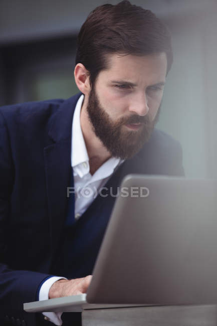 Внимательный бизнесмен, использующий ноутбук вне офиса — стоковое фото
