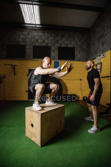 Два спортсмена работают над деревянной коробкой в фитнес-студии — стоковое фото