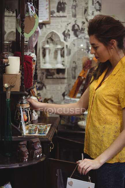Mulher olhando para frasco vintage na loja de antiguidades — Fotografia de Stock