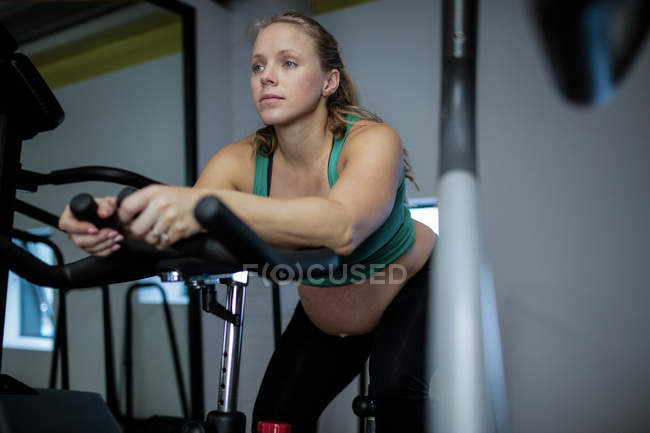 Вагітна жінка працює на тренажерному велосипеді в спортзалі — стокове фото