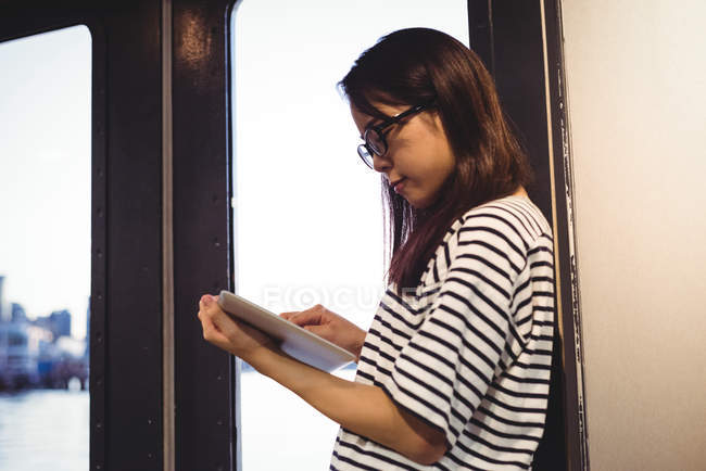 Молодая женщина опирается на стену во время использования цифрового планшета — стоковое фото