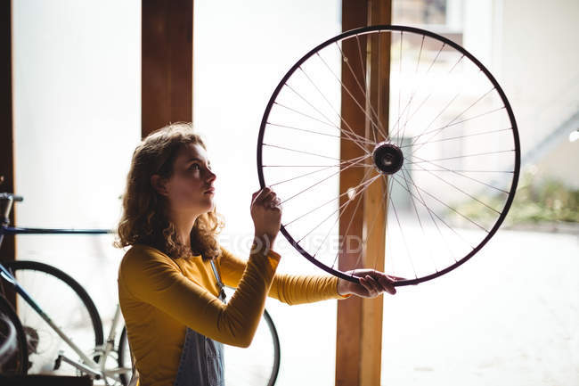 Mechanic examining a bicycle wheel in workshop — Stock Photo
