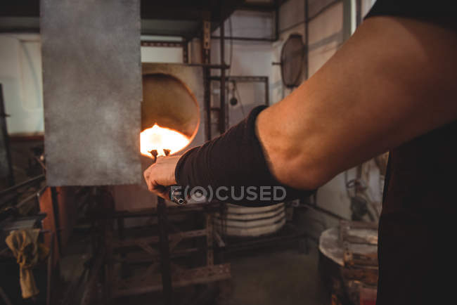 Image recadrée de verre chauffant de souffleur de verre dans le four à l'usine de soufflage de verre — Photo de stock