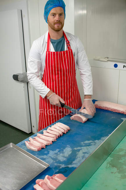 Retrato de açougueiro cortando carne no açougue — Fotografia de Stock
