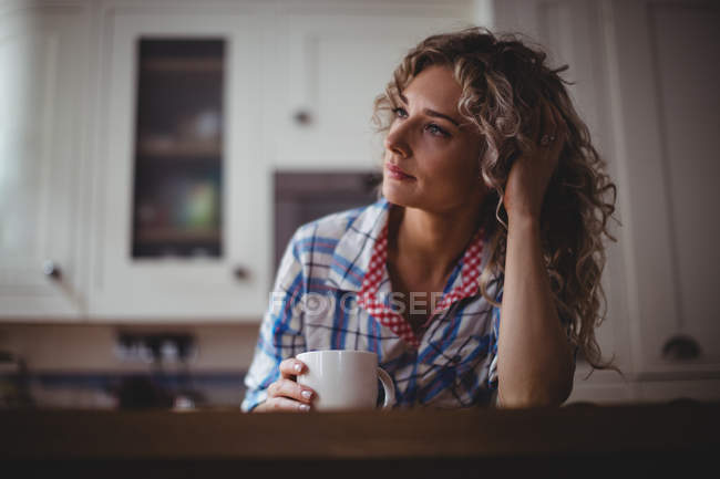 Femme réfléchie prenant un café dans la cuisine à la maison — Photo de stock