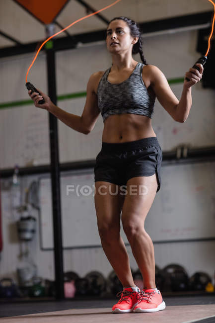 Vista de ángulo bajo de la mujer haciendo ejercicio con saltar la cuerda en el gimnasio - foto de stock