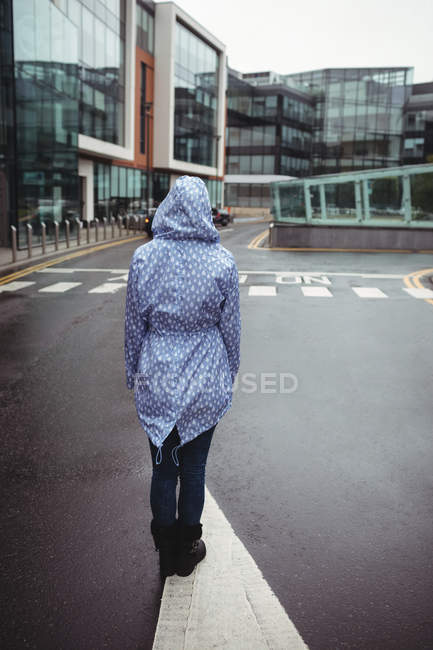 Вид сзади женщины, стоящей на улице во время дождя — стоковое фото