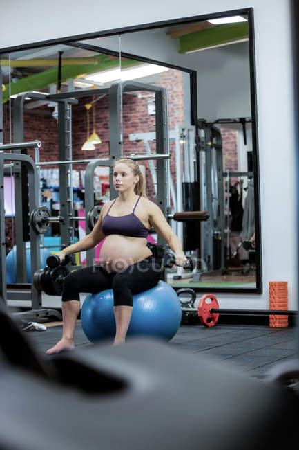 Donna incinta che solleva manubri in palestra — Foto stock
