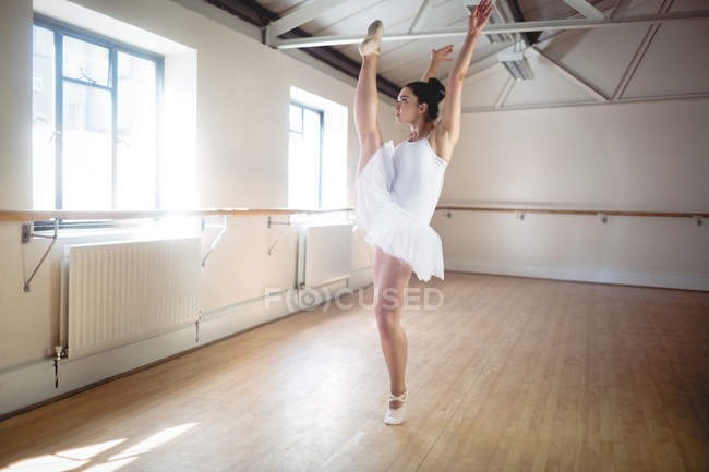 Joven bailarina en tutú blanco practicando danza de ballet en estudio - foto de stock