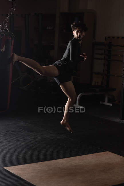 Boxer maschile che pratica pugilato con sacco da boxe in palestra — Foto stock
