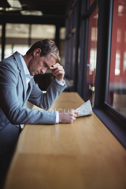 Tensed businessman reading newspaper in cafe — Stock Photo