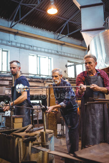 Equipe de sopradores de vidro que moldam um vidro nos blowpipes na fábrica de sopro de vidro — Fotografia de Stock
