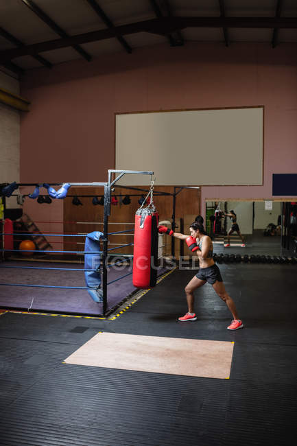 Boxer feminino praticando boxe com saco de perfuração no estúdio de fitness — Fotografia de Stock