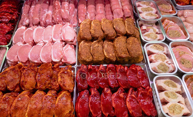 Variedad de carne marinada en mostrador en carnicería - foto de stock