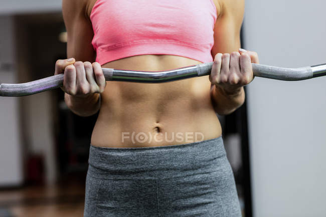 Mid-section of woman working out with barbell at gym — Stock Photo
