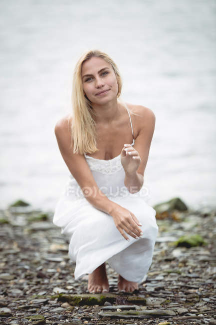 Portrait of carefree blonde woman crouching near river — Stock Photo