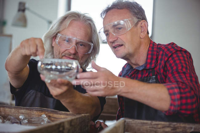Glassblower e um colega olhando vidraria na fábrica de vidro — Fotografia de Stock
