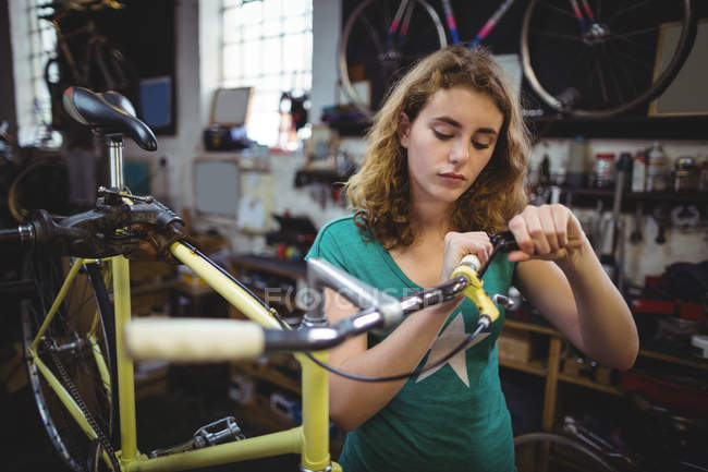 Mecánico examinando bicicleta en taller - foto de stock