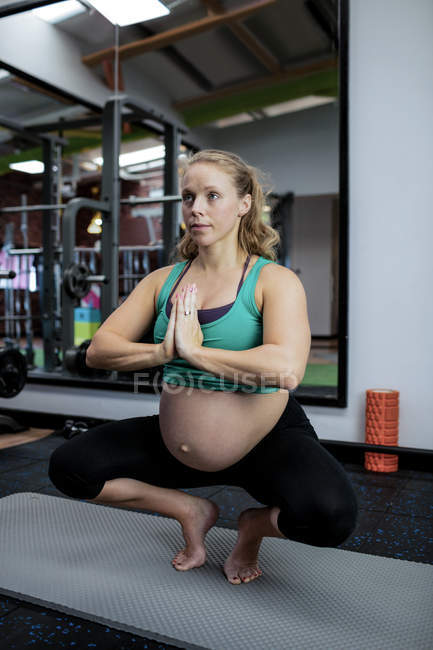 Pregnant woman performing yoga in gym — Stock Photo