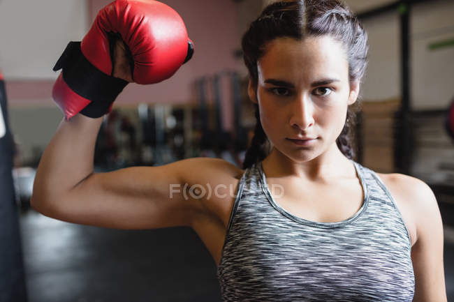 Portrait de boxeuse en gant de boxe montrant le muscle dans le studio de fitness et regardant la caméra — Photo de stock