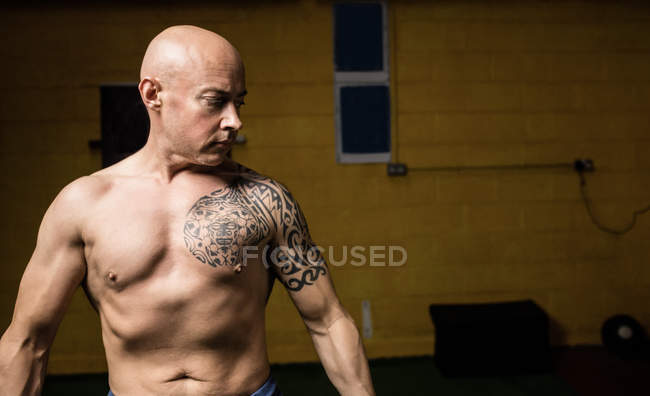Tattooed shirtless thai boxer posing in gym — Stock Photo