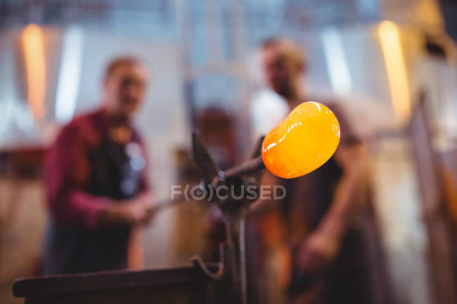 Стеклодувы, формирующие расплавленное стекло на стекольном заводе — стоковое фото