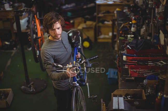 Mécanicien portant un vélo dans un atelier de vélo — Photo de stock