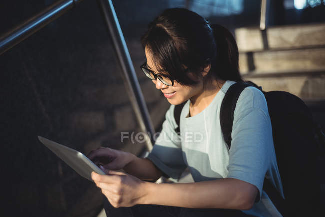 Jovem mulher sentada na escada e usando comprimido digital à noite — Fotografia de Stock