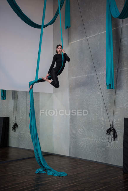 Жінка-гімнастка вправи на синій тканинній мотузці в фітнес-студії — стокове фото