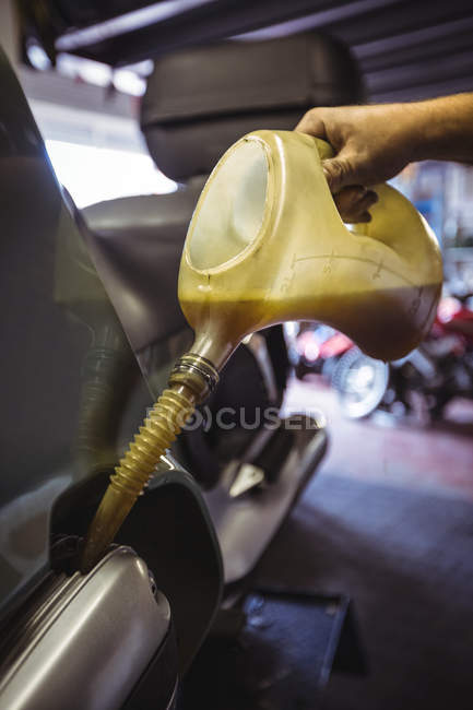 Mechanic pouring oil into oil tank at workshop — Stock Photo