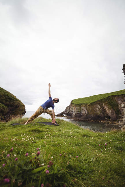 Man performing stretching exercise on cliff — Stock Photo