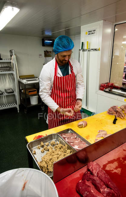 Мясник готовит курицу и стейк-ролл в мясном магазине — стоковое фото