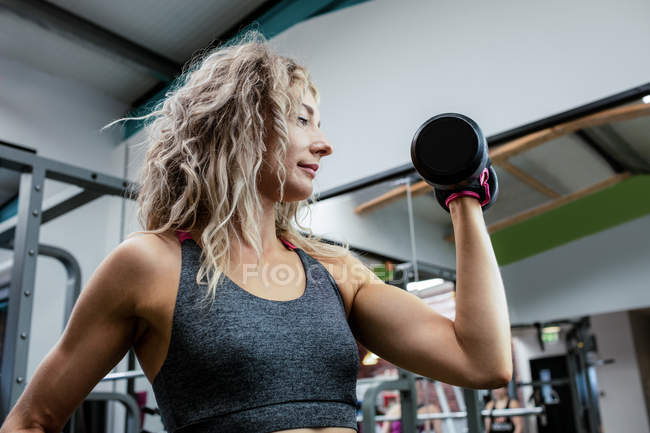Woman lifting dumbbell at gym — Stock Photo