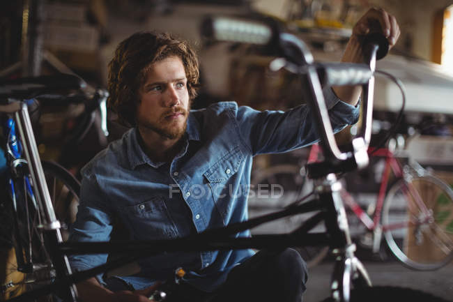 Mechanic examining bicycle in workshop — Stock Photo