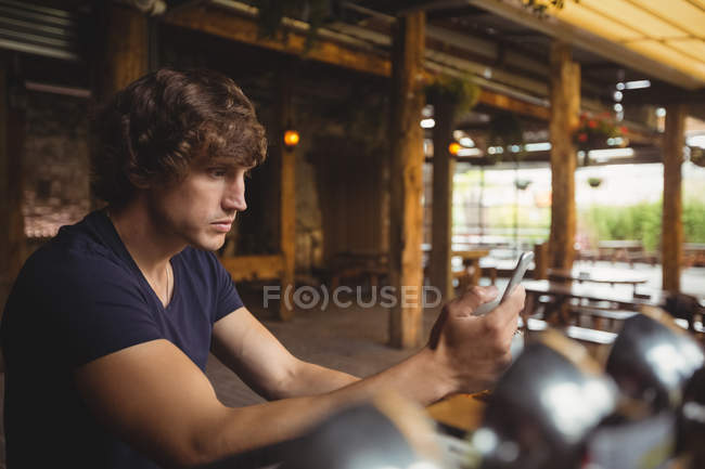 Uomo che utilizza il telefono cellulare nel bancone del bar al bar — Foto stock