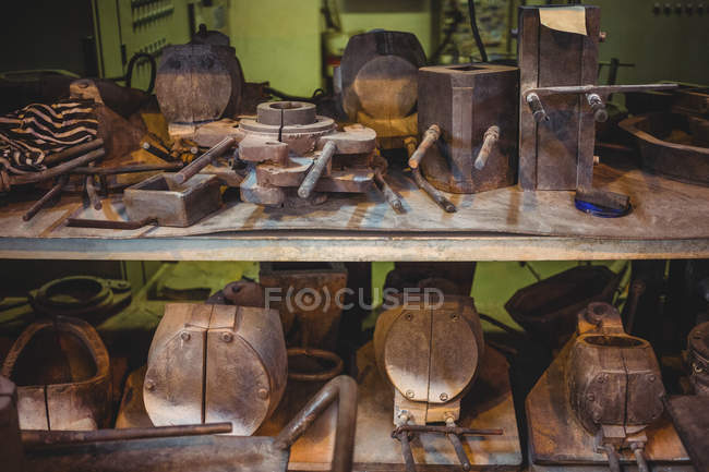 Moldes de metal para sopro de vidro dispostos na prateleira na fábrica de sopro de vidro — Fotografia de Stock