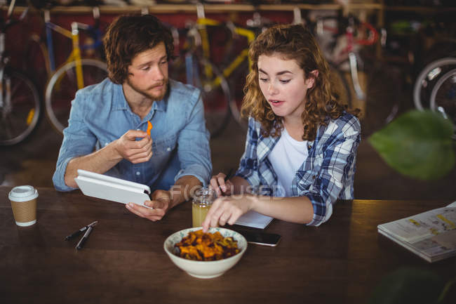 Mechanics interacting with each other while having breakfast in workshop — Stock Photo