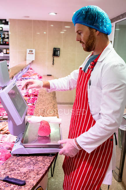 Metzger überprüft Fleischgewicht an Theke in Fleischerei — Stockfoto