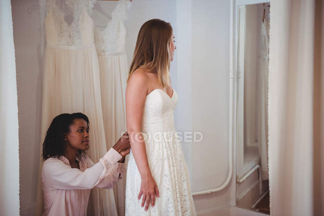 Donna che prova l'abito da sposa in uno studio con l'assistenza dello stilista — Foto stock