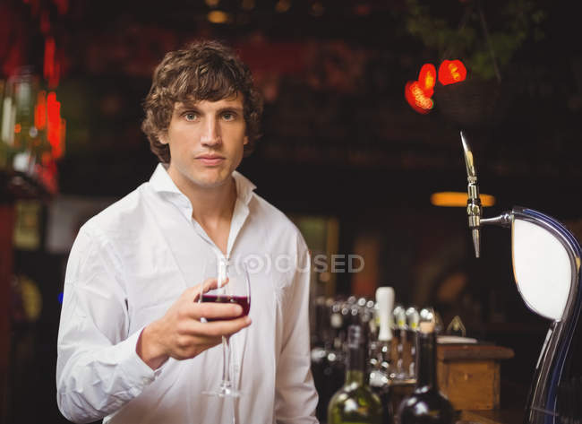 Retrato de bar tender vaso de vino tinto en el mostrador del bar - foto de stock