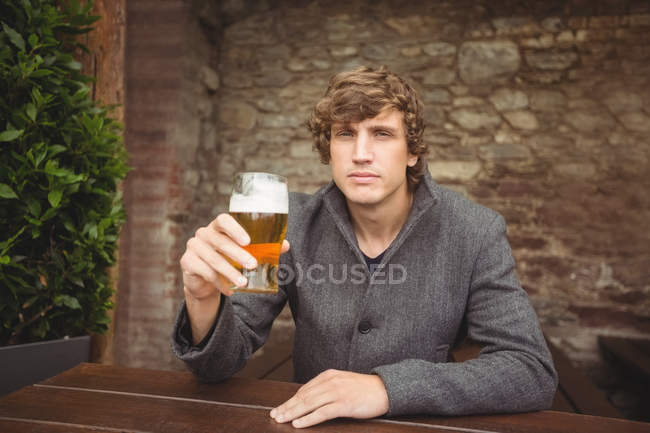 Retrato del hombre sosteniendo un vaso de cerveza en el bar - foto de stock