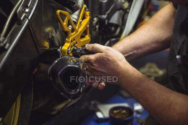 Primo piano del meccanico che esamina la moto in officina — Foto stock