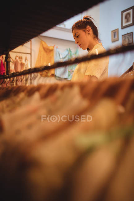 Жінка вибирає одяг на вішалках в магазині одягу — стокове фото