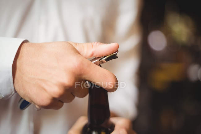 Close-up do barman abrindo uma garrafa de cerveja no balcão do bar — Fotografia de Stock