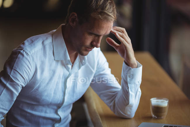 Homem de negócios tenso sentado no café com uma xícara de café — Fotografia de Stock