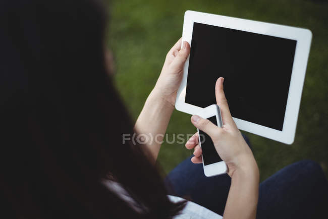 Primer plano de la mujer usando tableta digital y teléfono móvil - foto de stock