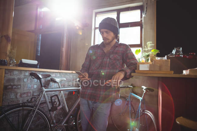 Man using mobile phone in bicycle shop — Stock Photo